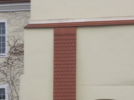 Unterhalb der Gesimsausdeckung aus Bibern an der Fassade