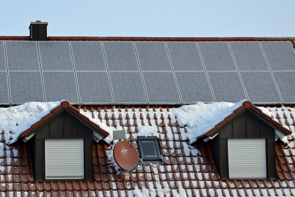 Schneebedecktes Dach mit Solarmodulen