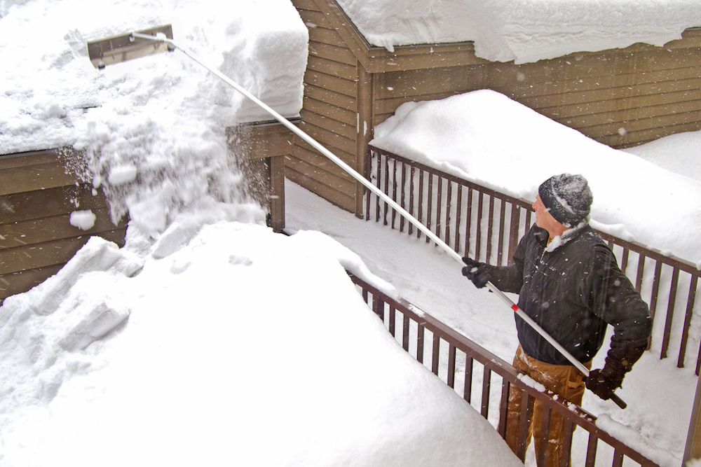 Mann beseitigt Schnee vom Dach - Gefahr Dachlawine